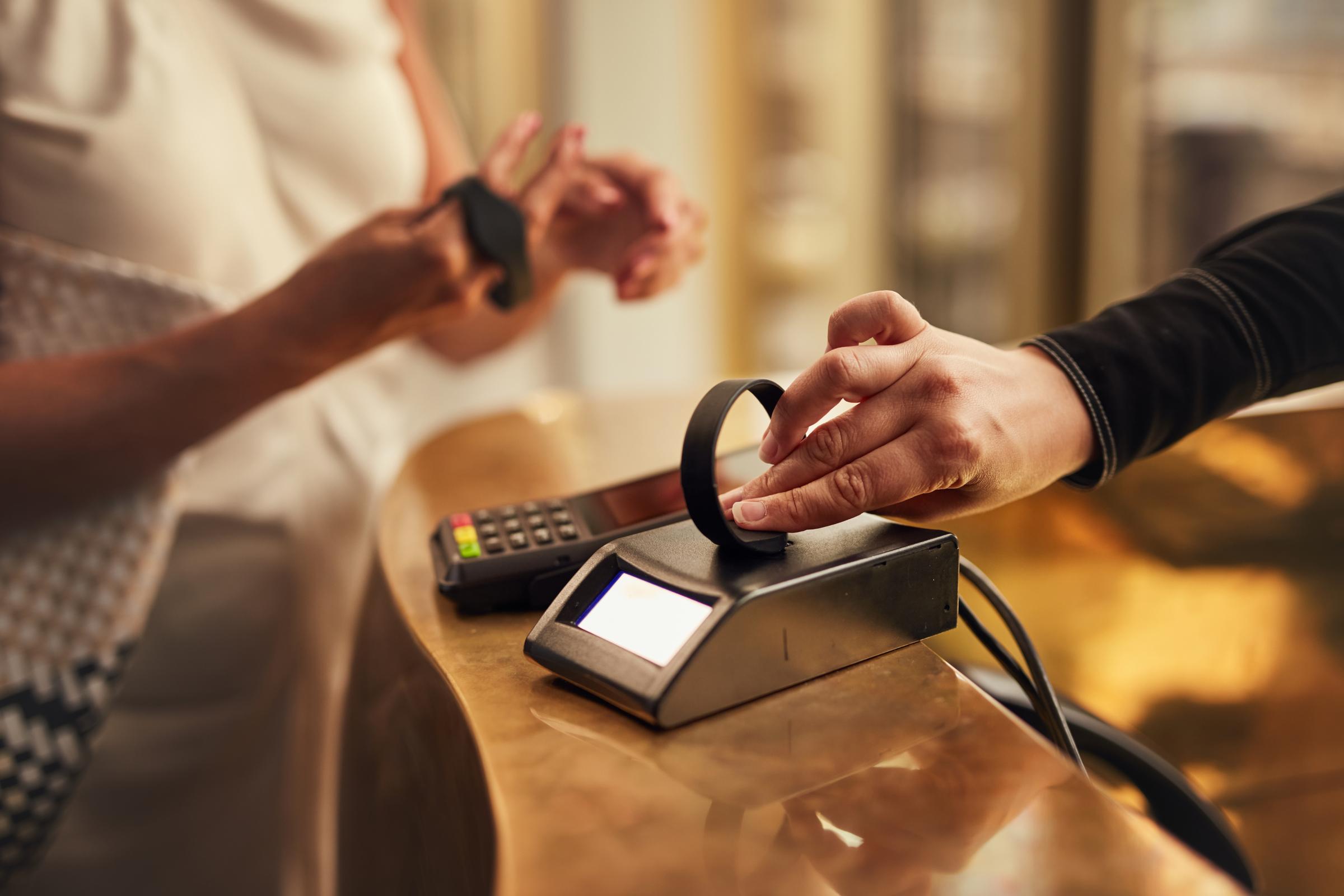 Persona che effettua un pagamento contactless con un smartwatch su un terminale di pagamento