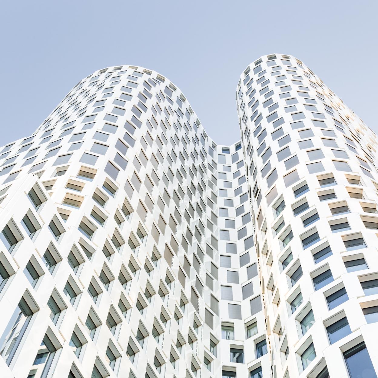 Krum moderne hvid bygning mod en klar blå himmel.