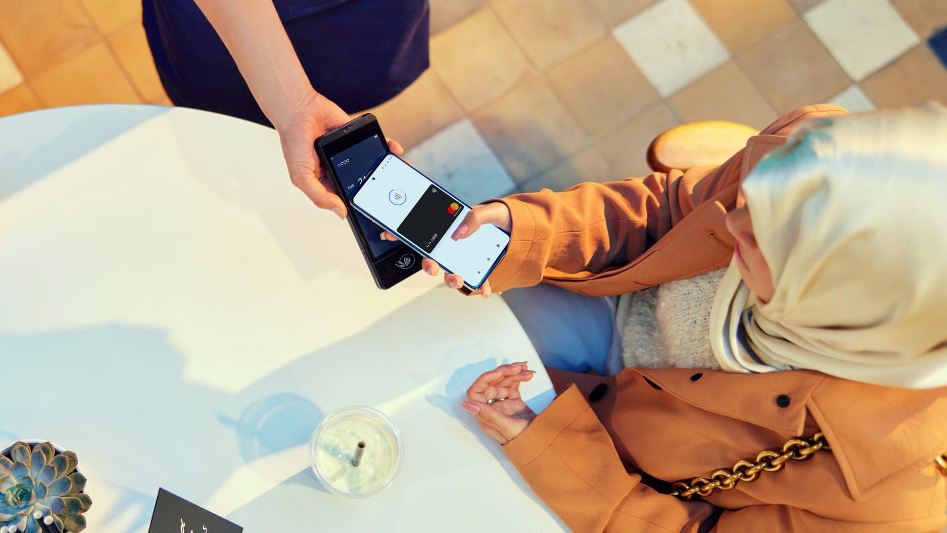 Två personer som behandlar en mobil betalning med en smartphone med Adyen-gränssnitt.