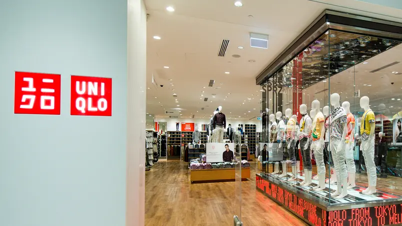 Inside view of a clothing store with mannequins on display and brand logos on the wall.