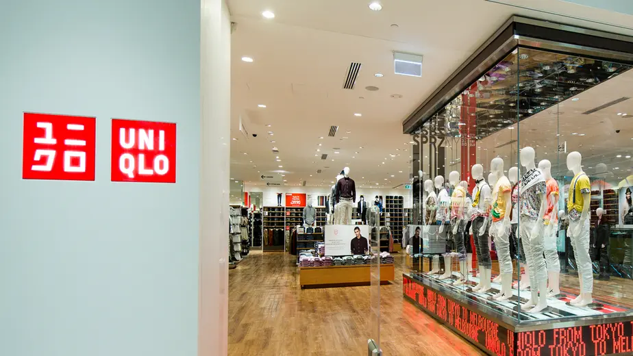 Inside view of a clothing store with mannequins on display and brand logos on the wall.