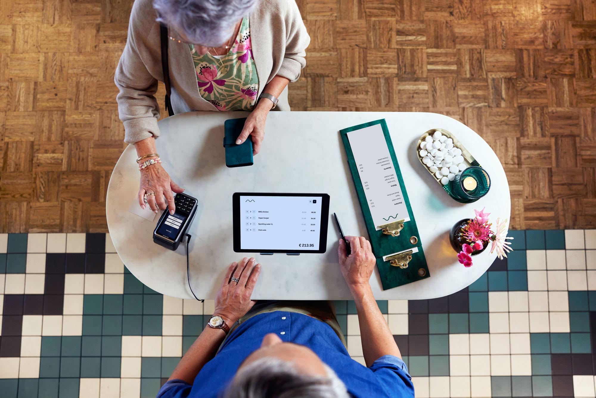 A woman at a restaurant selecting a donation amount on Adyen's V400m terminal.