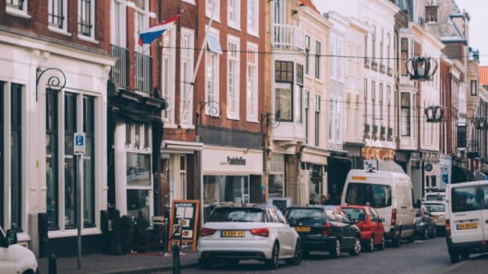 A bustling European street with historic buildings and parked cars.