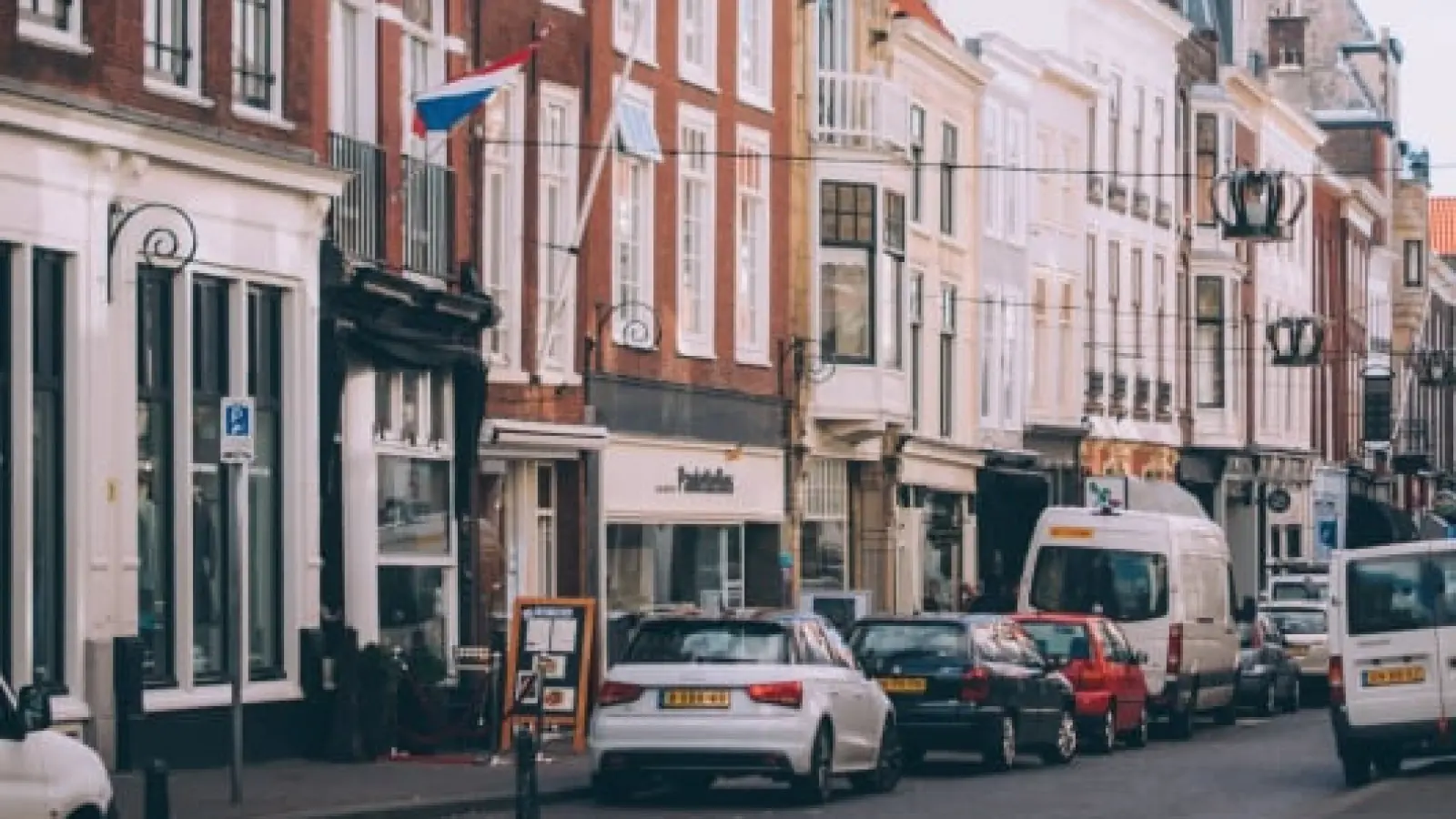 A bustling European street with historic buildings and parked cars.