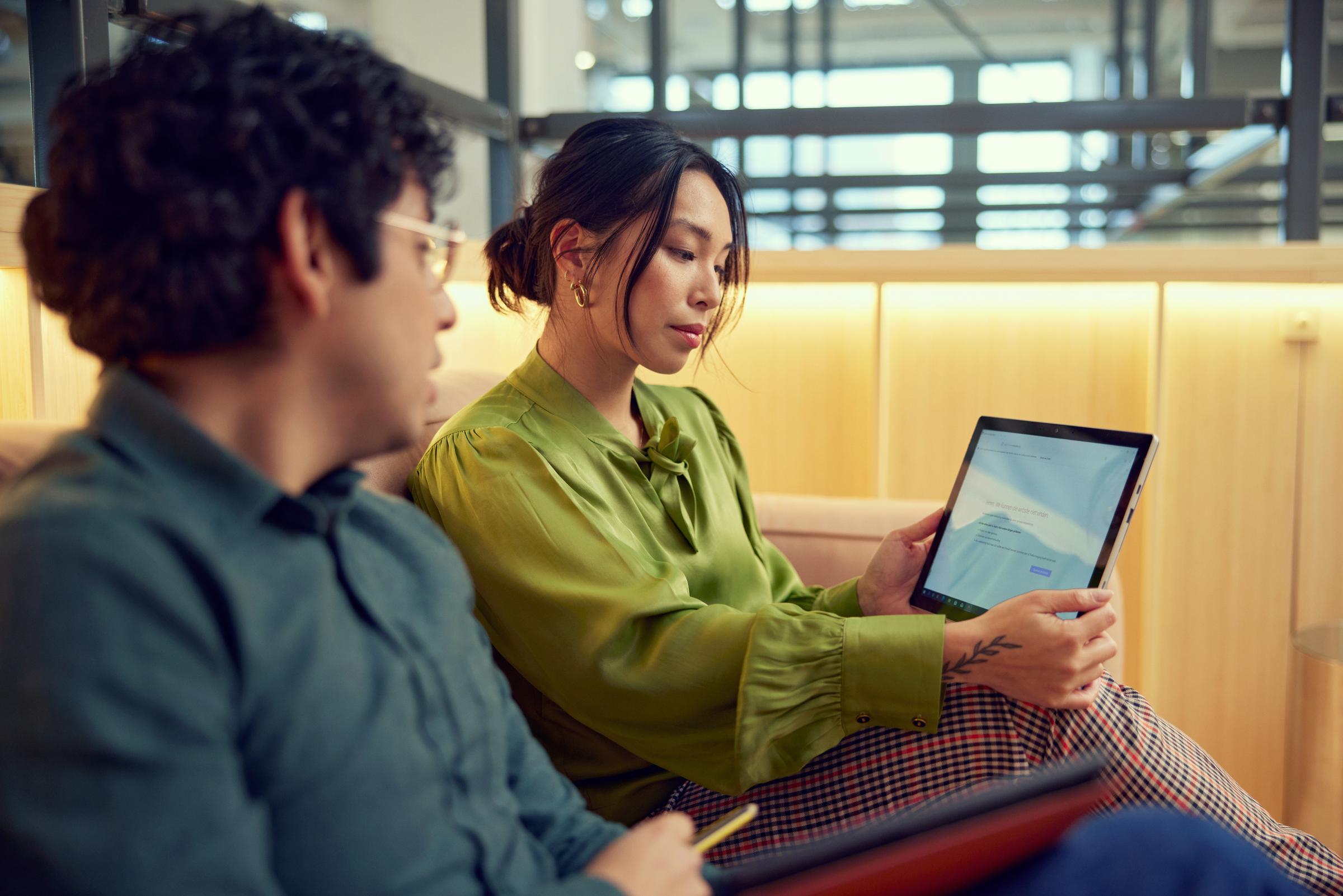 Dois colegas de trabalho no escritório da Adyen discutindo sobre um tablet