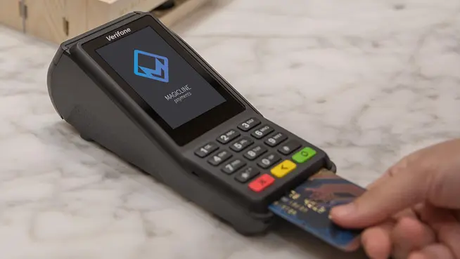 Menschenhand verwendet eine Kreditkarte auf einem Verifone-Zahlungsterminal mit Adyen-Checkout-Bildschirm.