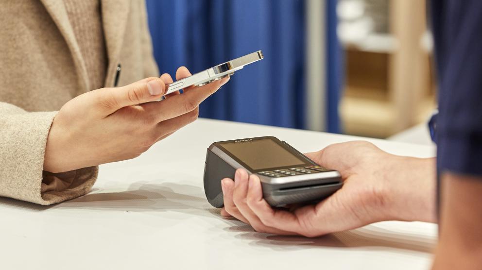 Customer making a contactless payment using a smartphone over a card terminal