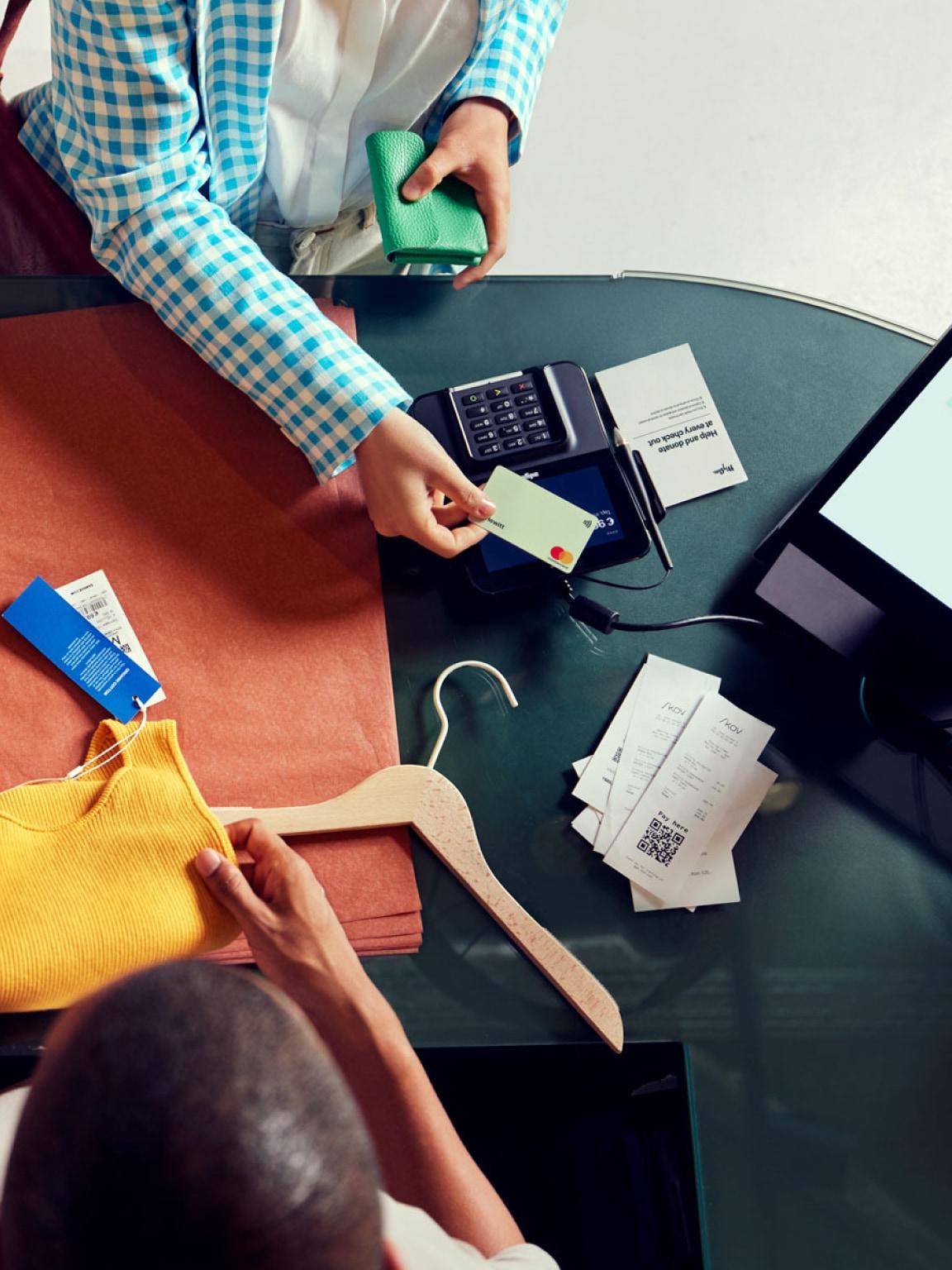 Pessoa a fazer um pagamento a usar um leitor de cartões Adyen numa caixa de retalho