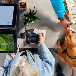 Översikt av en kund som gör ett betalning med en Adyen-terminal med en hund som tittar på