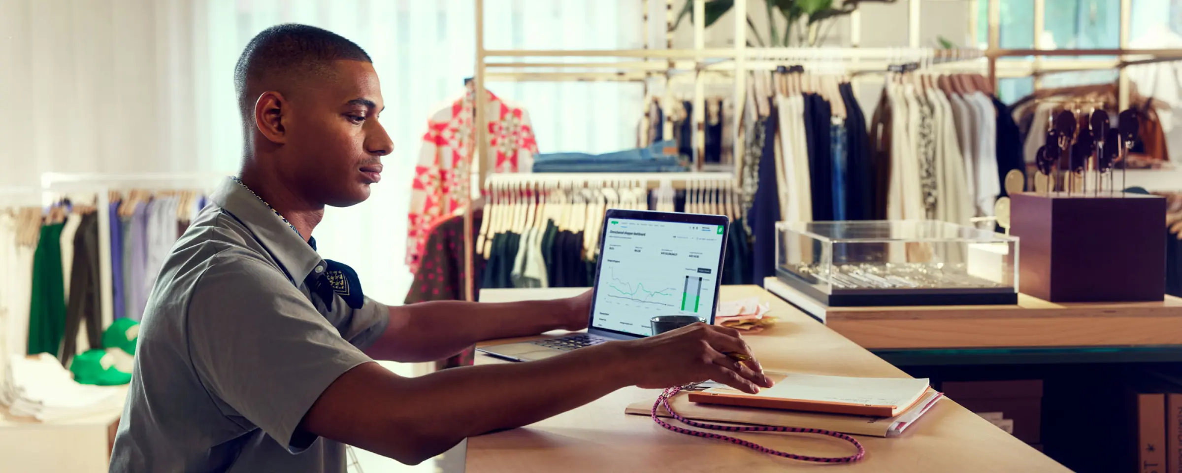 Man analyzing Adyen revenue charts on a laptop in a retail store.