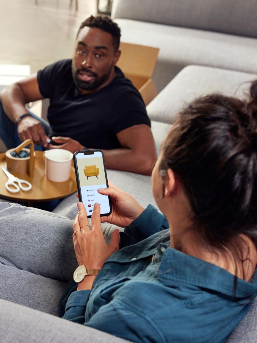 Persoon die een mobiele telefoon gebruikt met het betaalscherm van Adyen, een andere persoon kijkt toe.