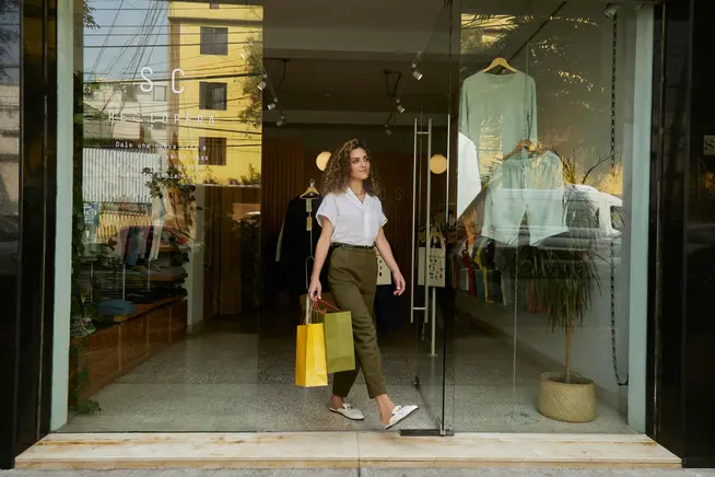 Cliente saliendo de una boutique con bolsas de compras.