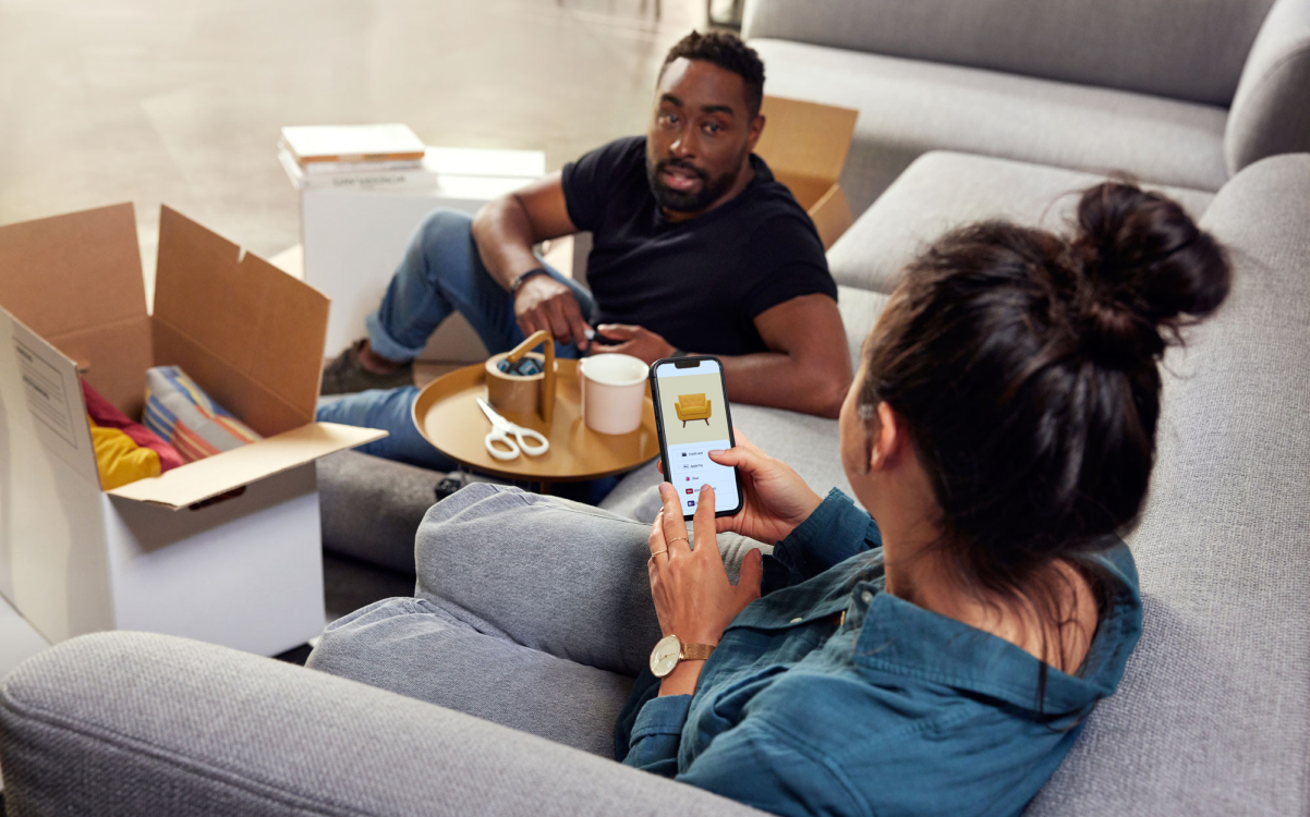 Una persona seduta su un divano che mostra a un'altra persona uno schermo di pagamento Adyen su uno smartphone.