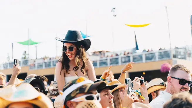 Woman on sitting on friends shoulders at a concert