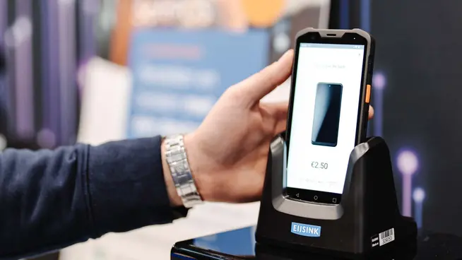 Hand houdt een mobiel apparaat vast met een betalingstransactie op het Adyen-scherm