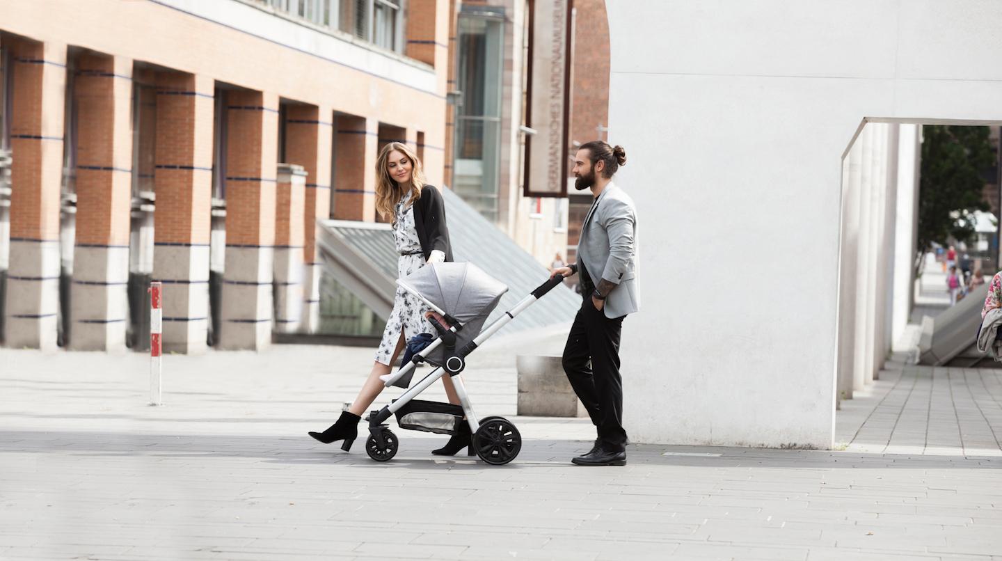 Ein Mann und eine Frau, die mit einem Kind im Kinderwagen auf der Straße gehen