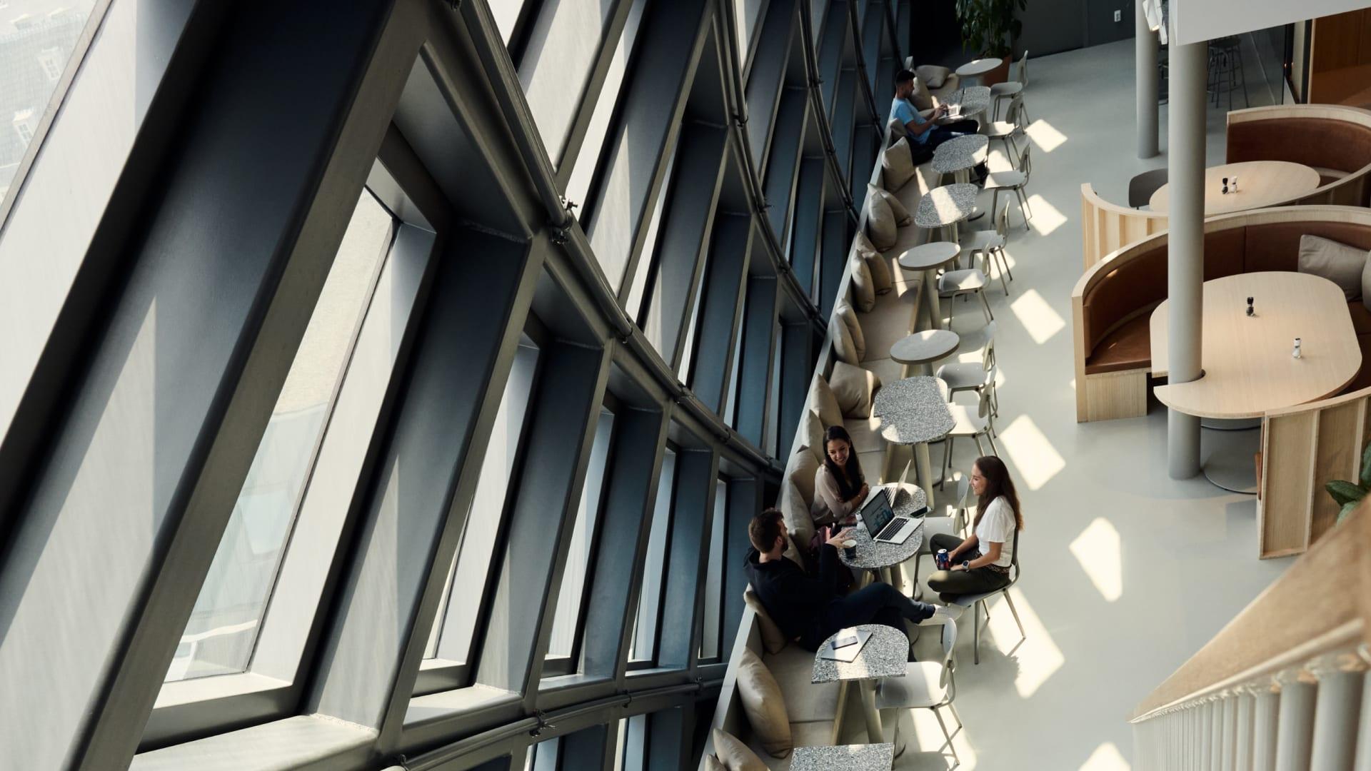 People working and interacting in a Adyen office space with large windows and lounge areas.