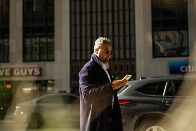 A person using a mobile device near a car with a payment terminal provided by Adyen.