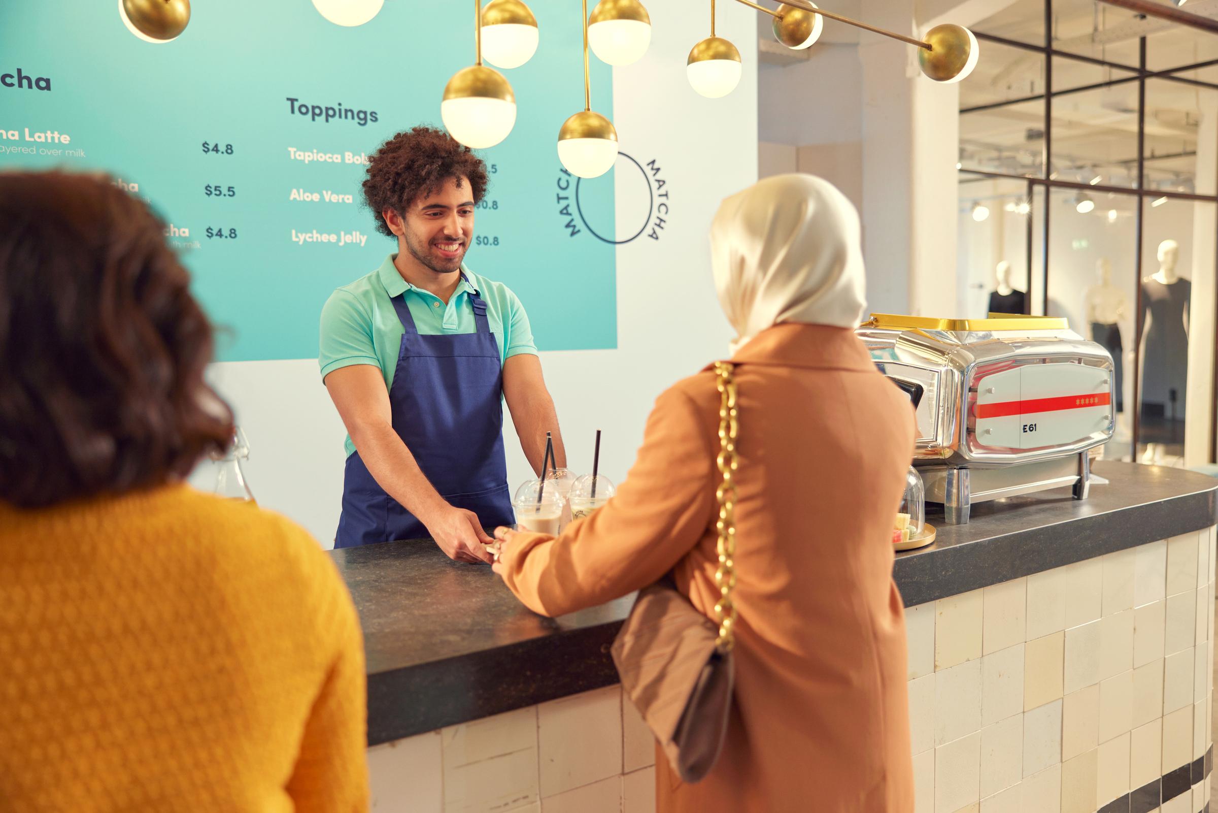 A woman receiving a tray with bubble tea a beverage stand.
