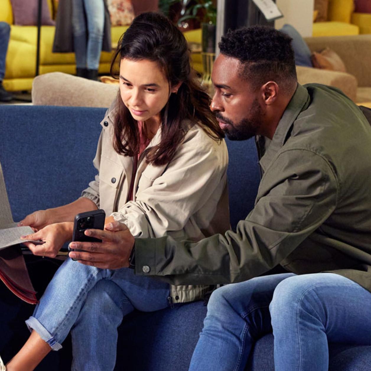 Two people sitting closely, looking intently at a smartphone.