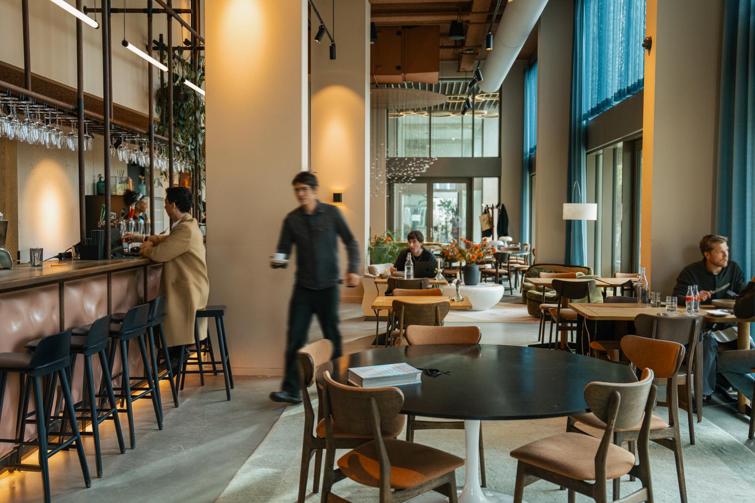 Modern café interior with customers, staff, and Adyen payment terminals visible.