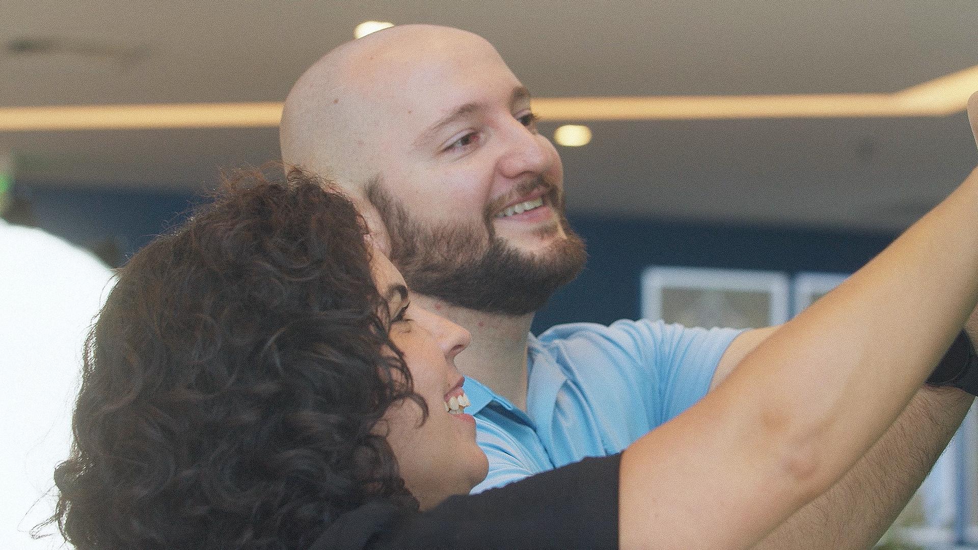 Duas pessoas sorrindo e tirando uma selfie juntas.