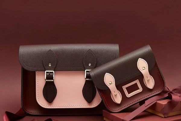 Two stylish satchel handbags with ribbon on a burgundy background.