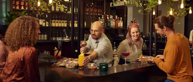 Group of people enjoying drinks and conversation at a cozy bar.