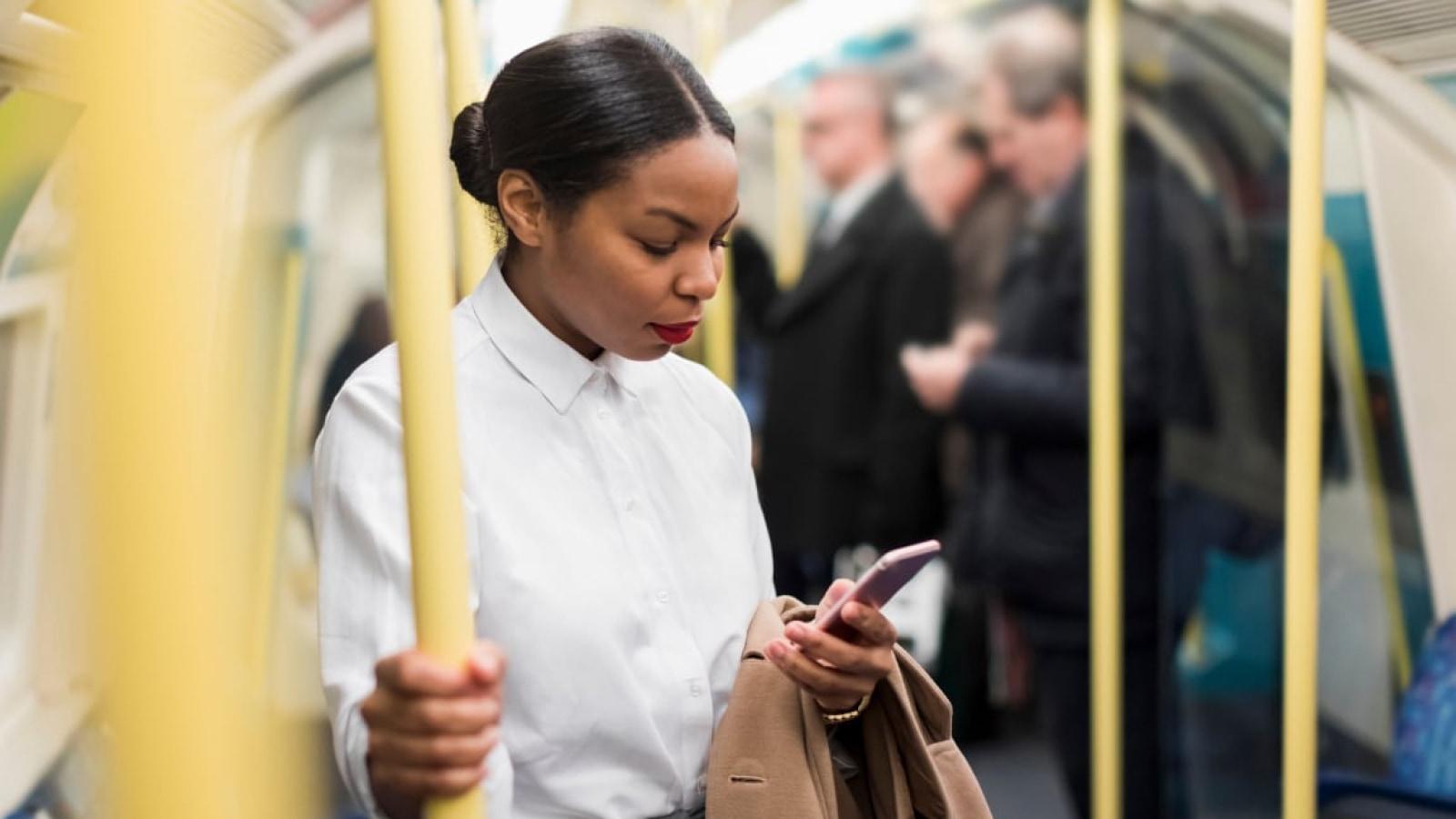Woman standing in the subway, engrossed in her smartphone.