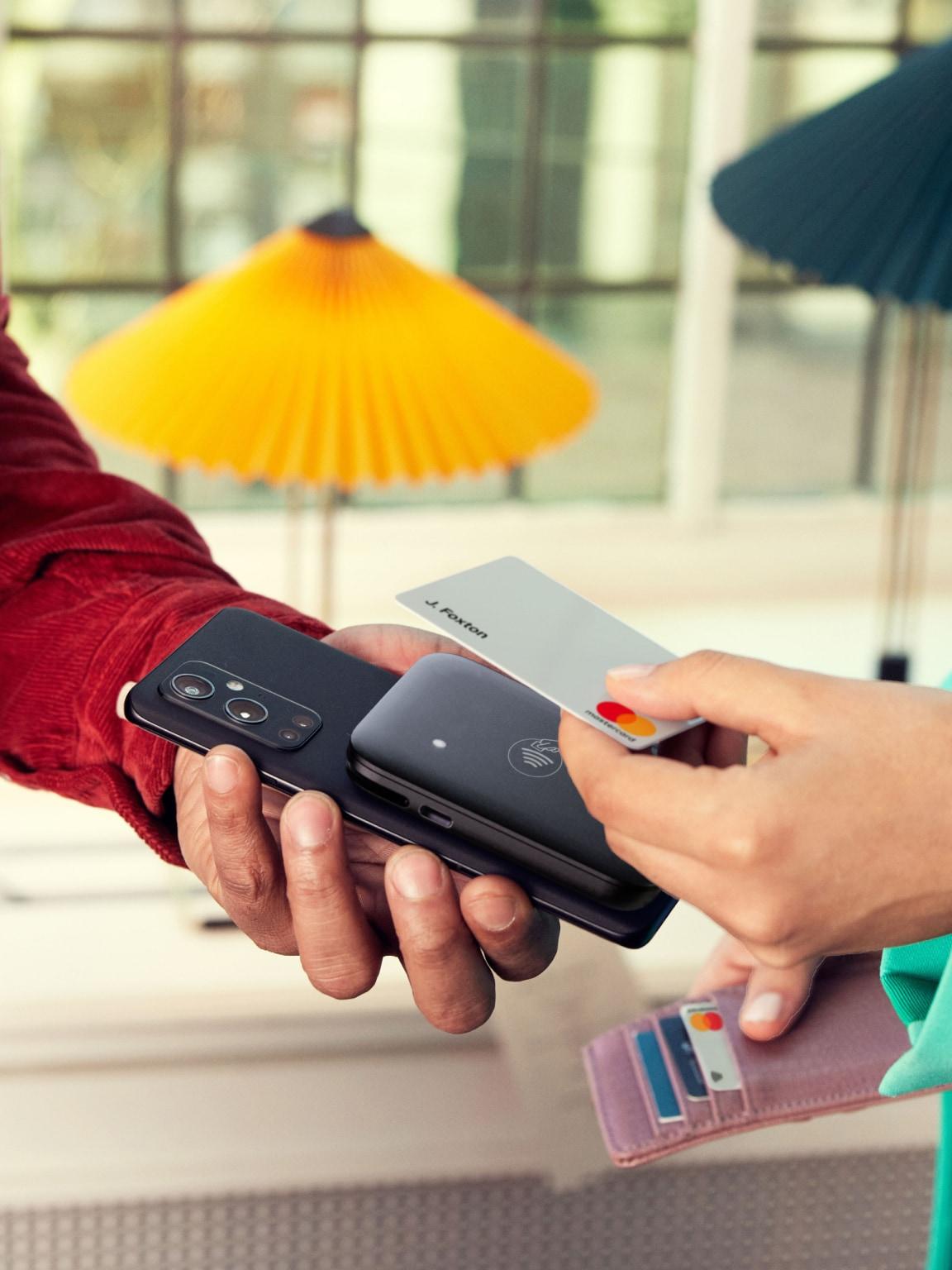 Due persone che eseguono un pagamento senza contatto utilizzando uno smartphone e una carta con tecnologia NFC.