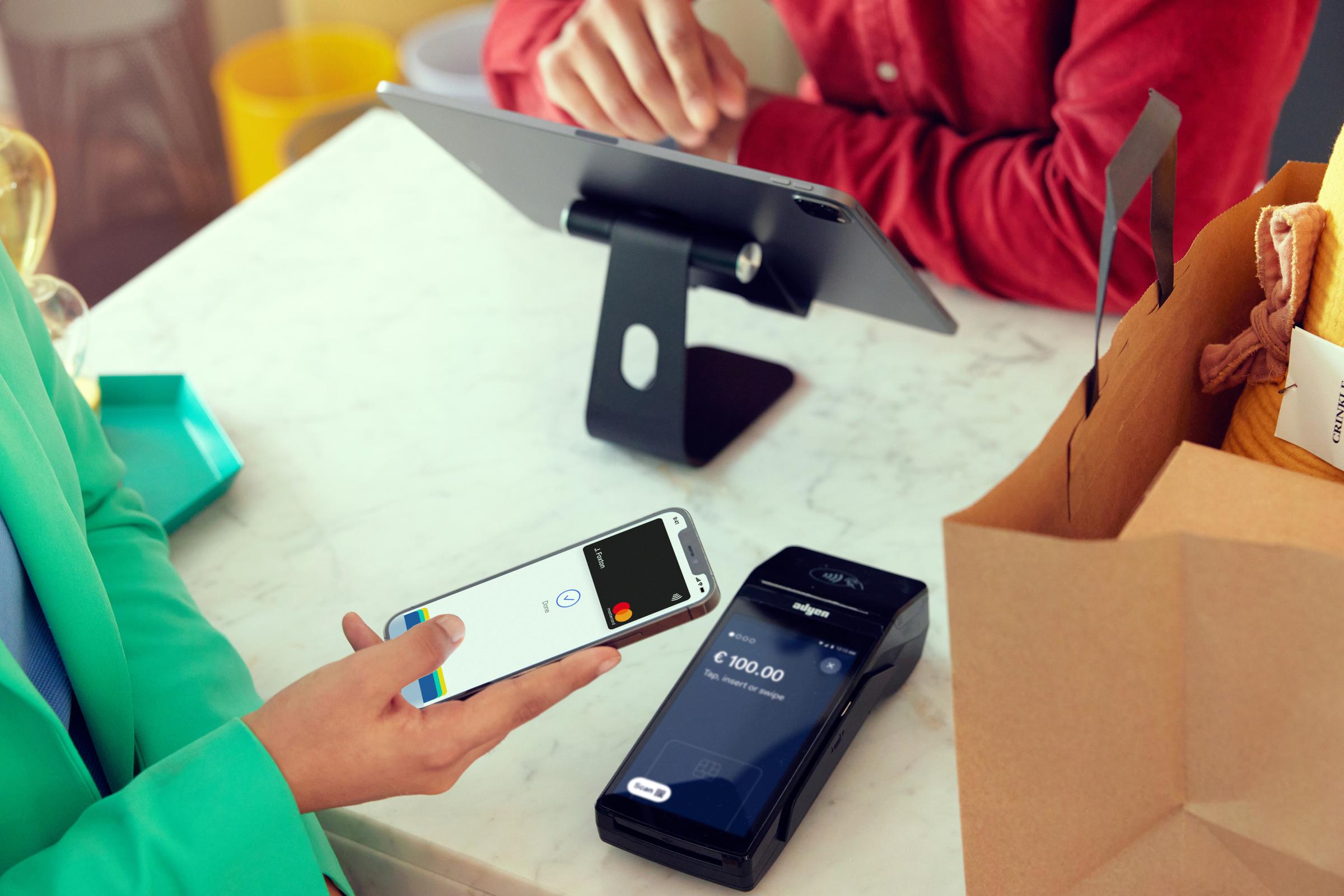 Person som betaler med telefon på en Adyen-terminal i en klesbutikk