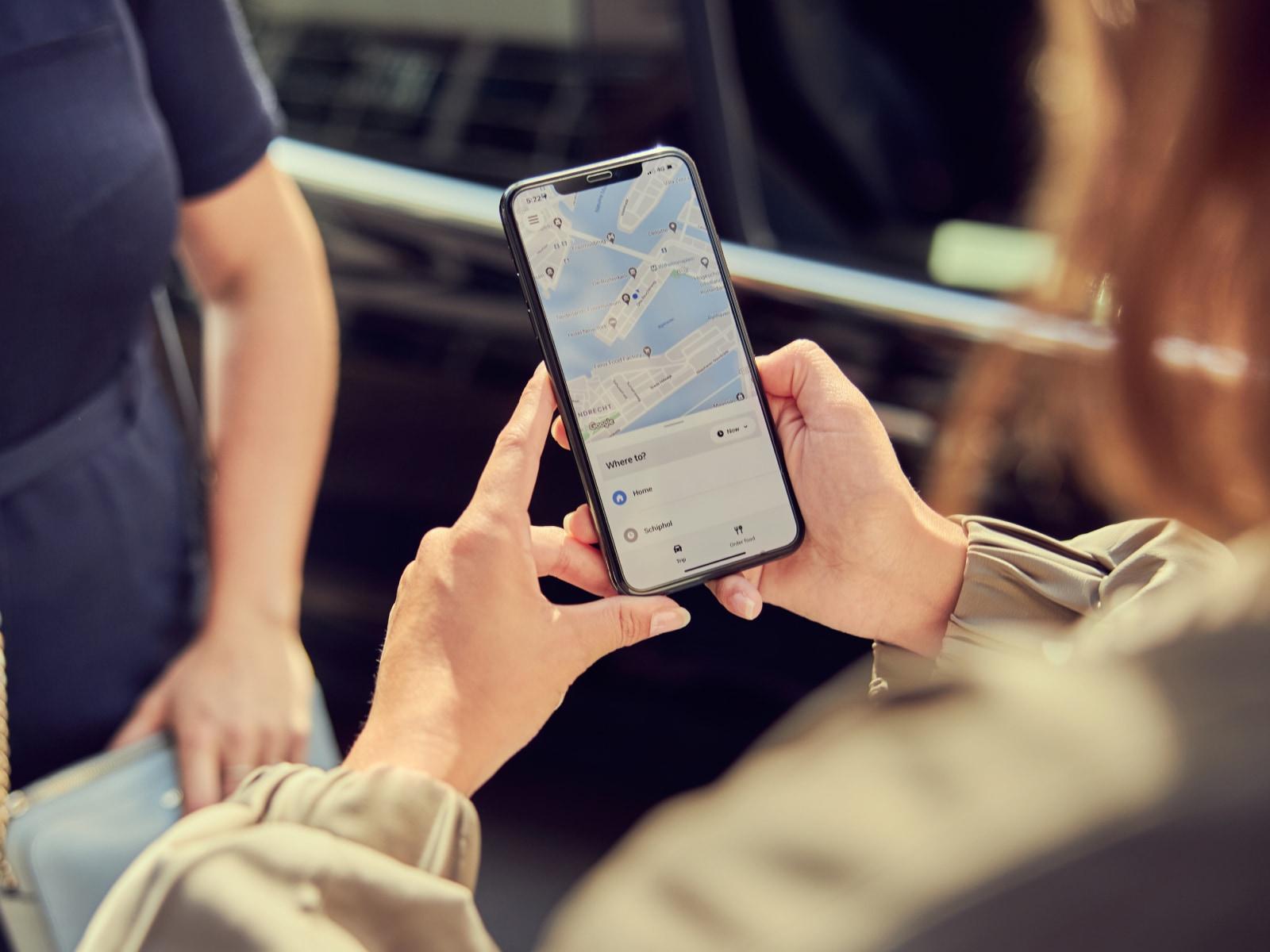 Close-up of a person's hands holding a smartphone with a map application on the screen.