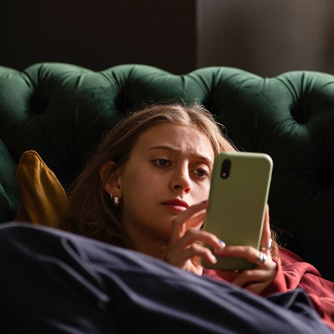 A woman shopping on her phone from the comfort of her couch.