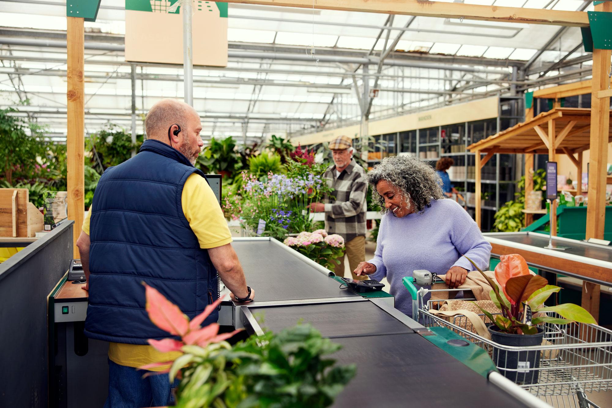 Ein Kunde an der Theke in einem Gartenzentrum zahlt für Pflanzen und spendet über das Adyen-M400-Terminal.