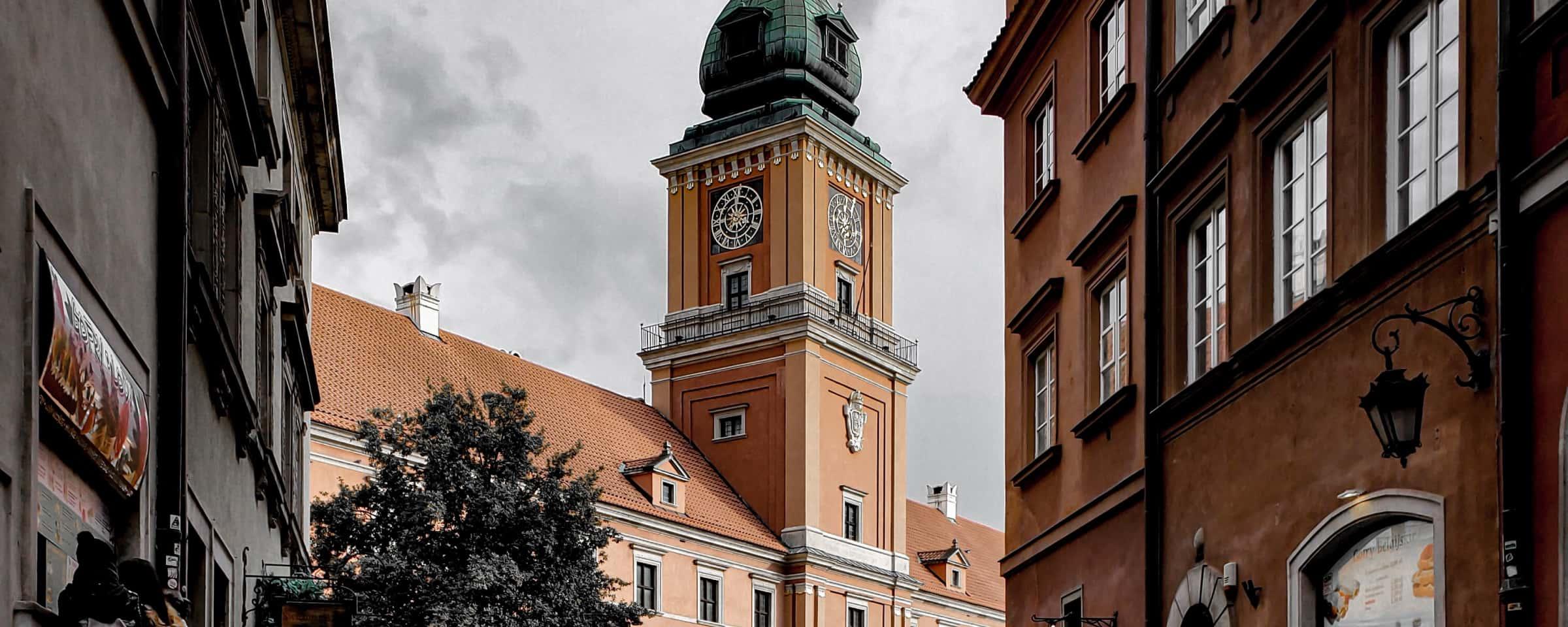 Historisk klocktorn som reser sig ovanför orange byggnader på en molnig dag.
