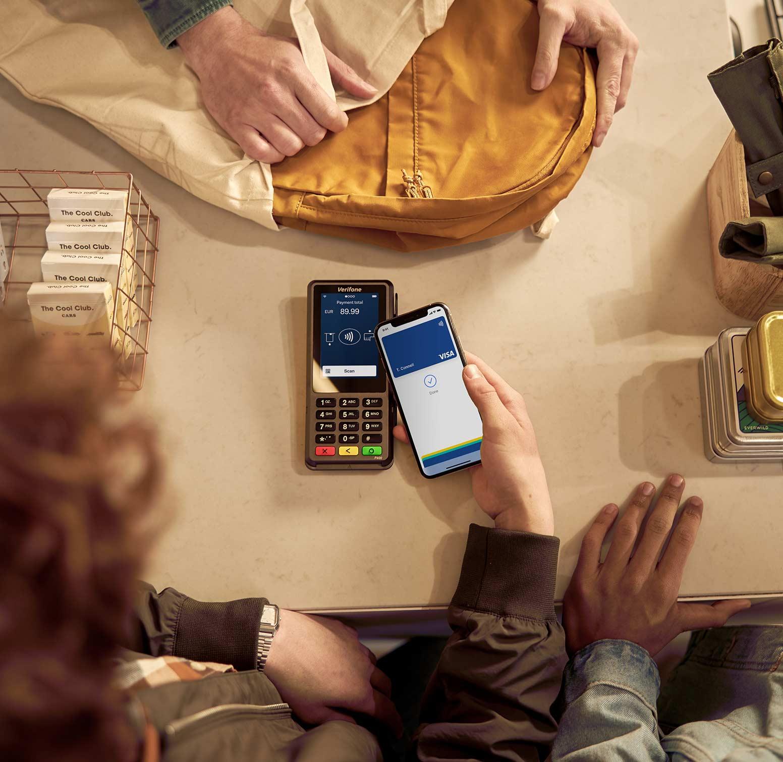 Dos personas realizando un pago móvil mediante un terminal POS sin contacto.