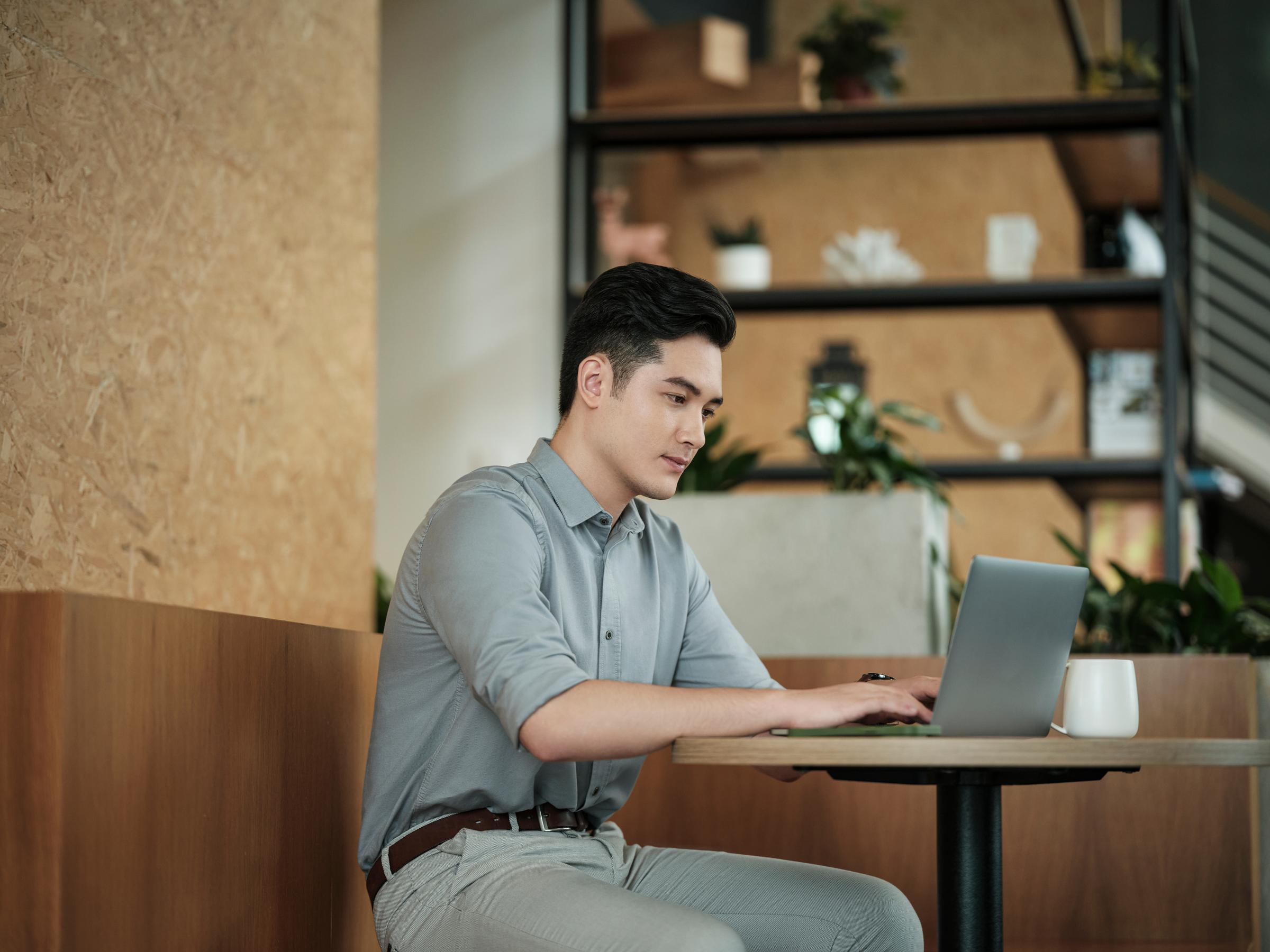Asian guy sitting in a cafe using laptop alone