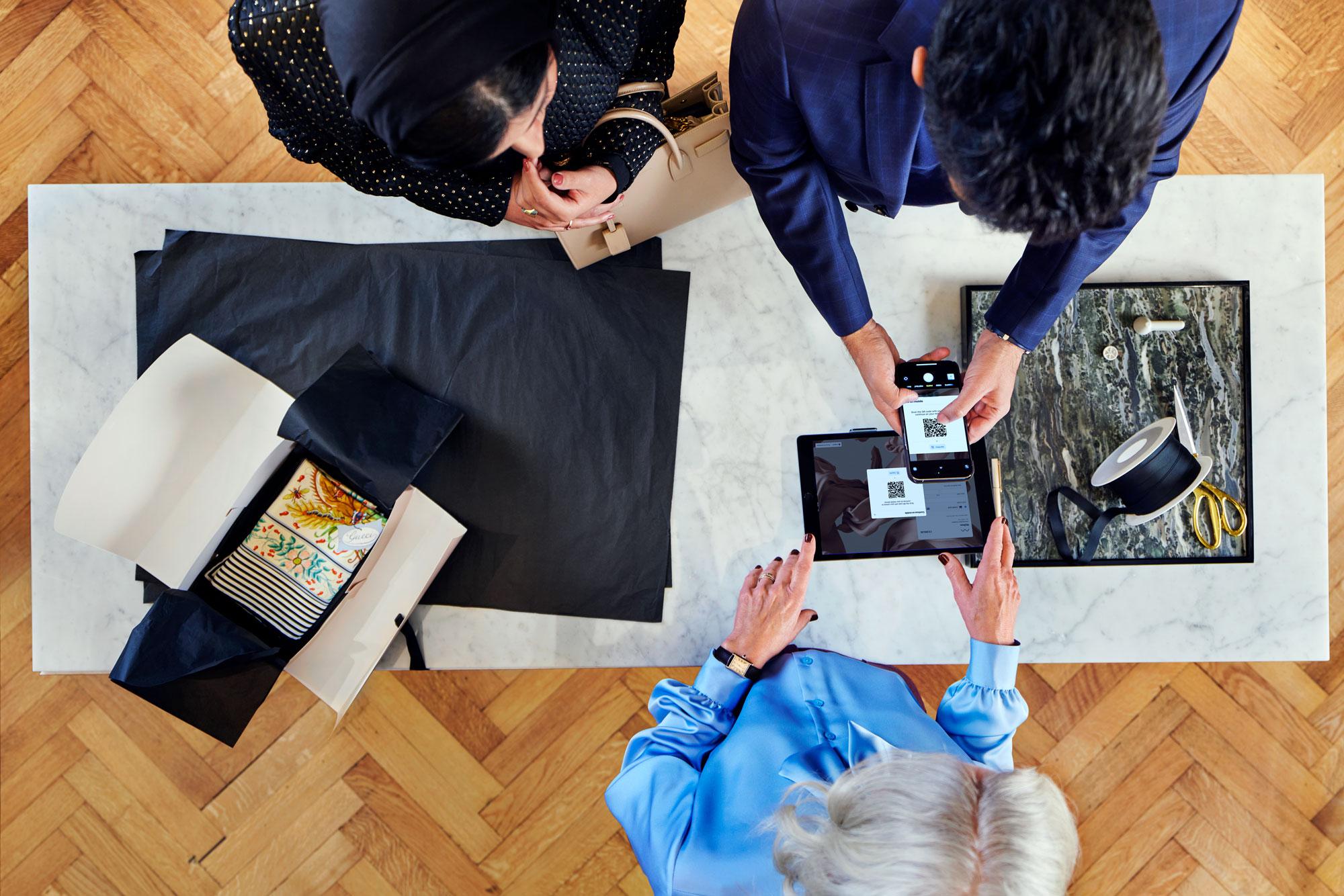 Um casal em uma loja de moda de luxo, pagando sua compra usando o Adyen's Pay by link.