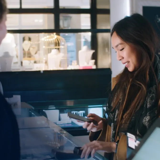 Mujer utilizando un smartphone para realizar un pago en la caja de una joyería.
