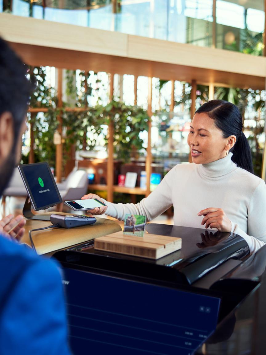 Client effectuant un paiement sans contact en utilisant un smartphone à une caisse avec terminal Adyen.