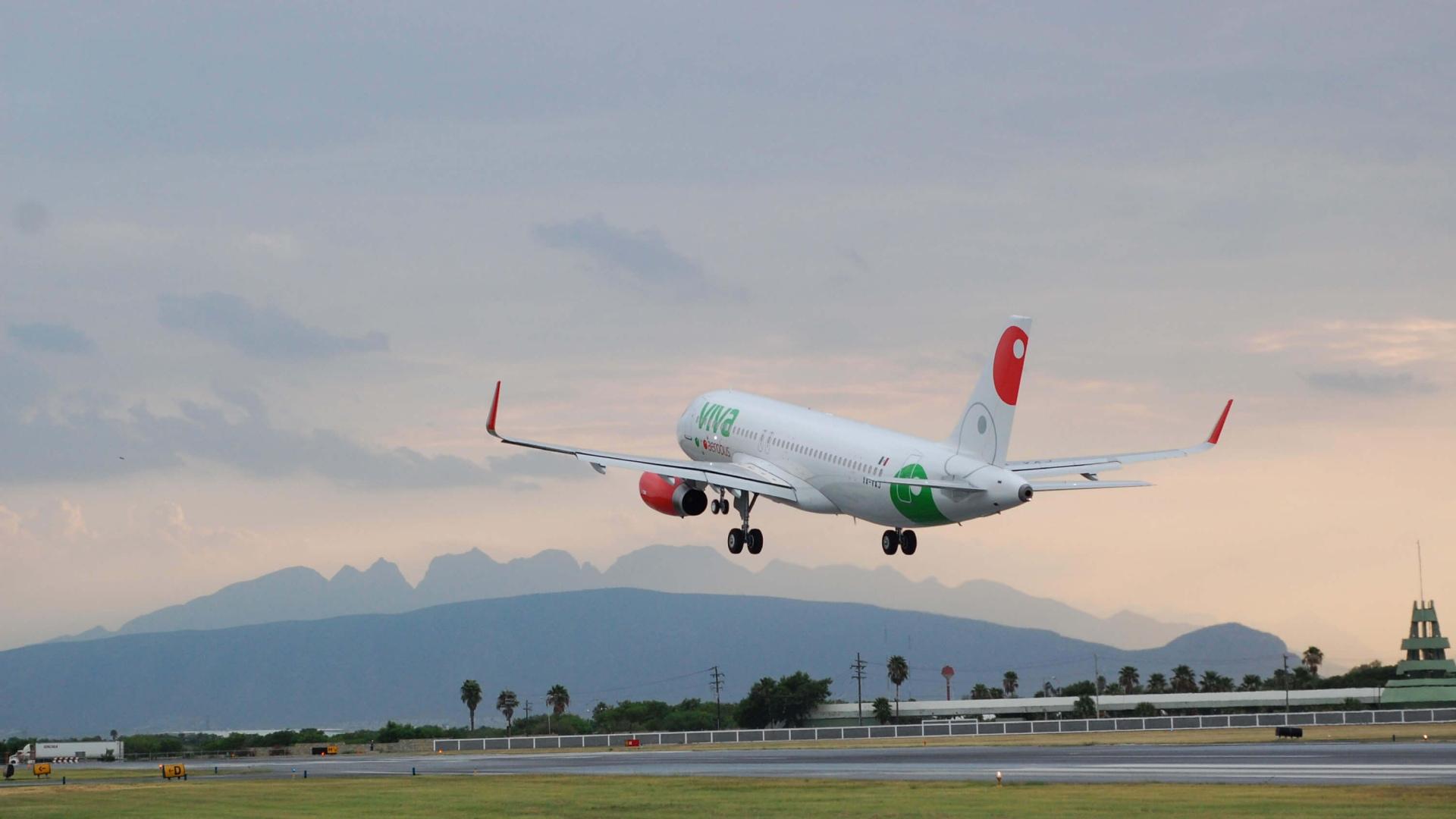 Commercial aircraft taking off with mountains in the background at dusk.