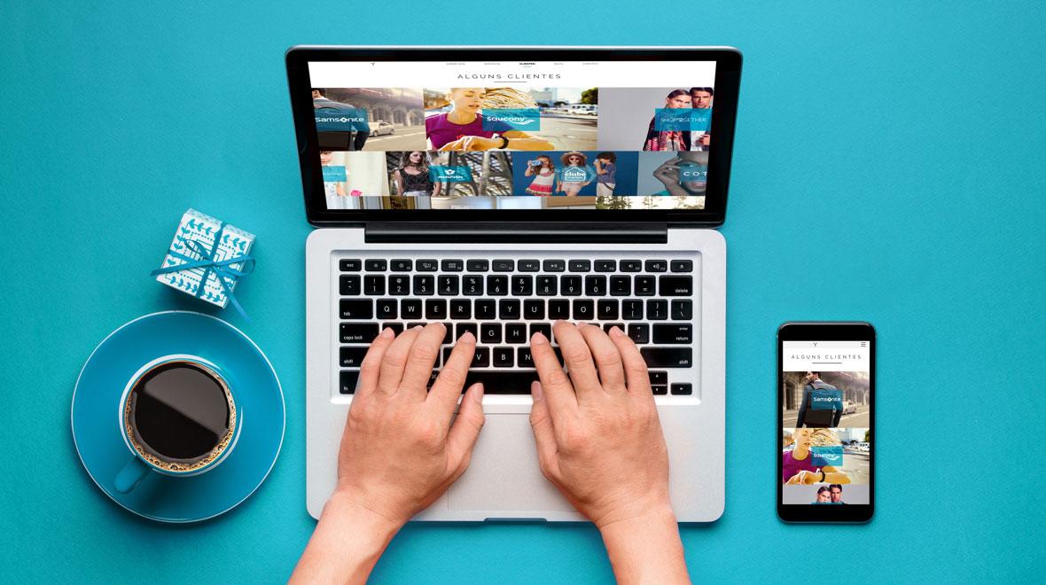 Pessoa navegando em uma galeria de clientes em um laptop ao lado de uma xícara de café e um smartphone exibindo o mesmo conteúdo.