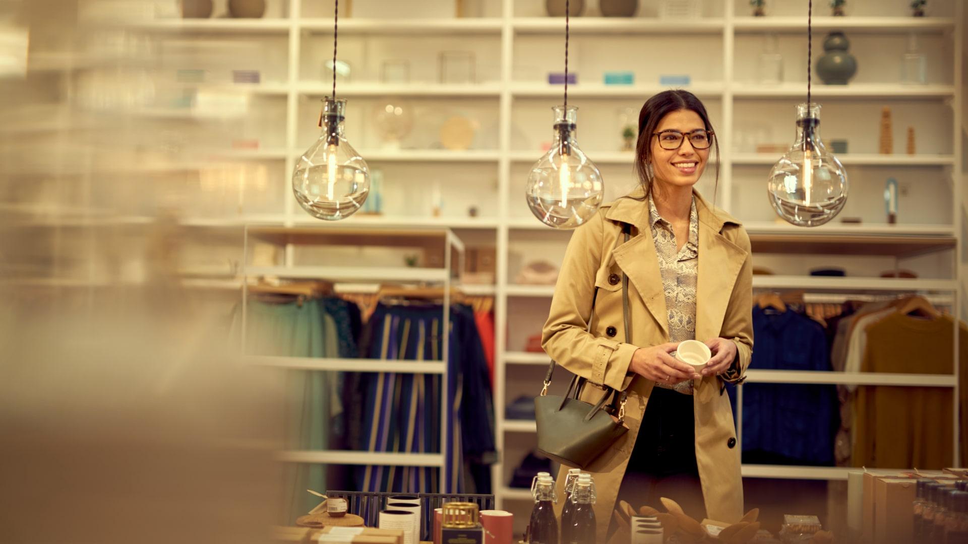 Mujer sonriendo comprando en una boutique con ropa y decoración para el hogar de estilo.