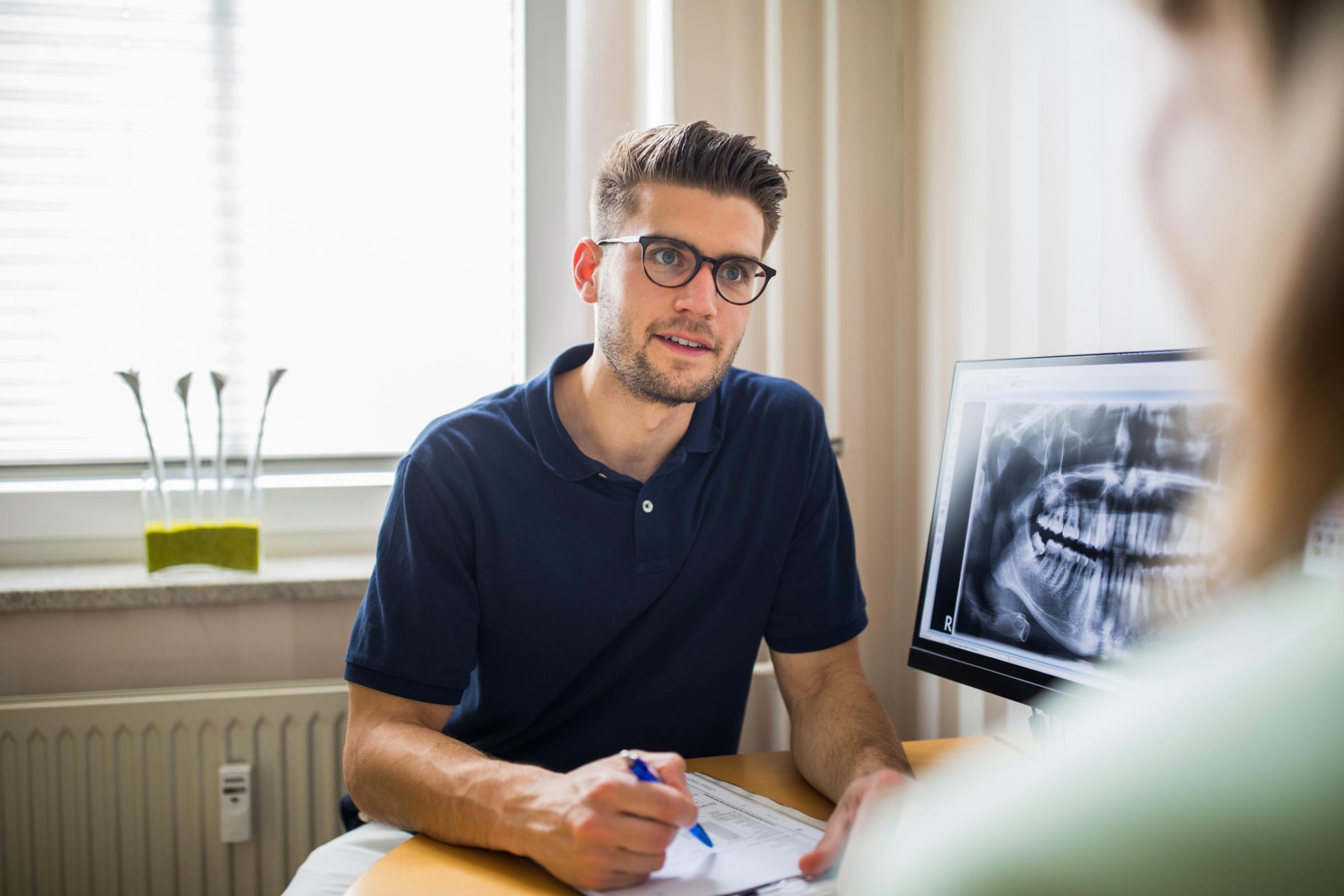 Male dentist talking with female patient in his clinic office