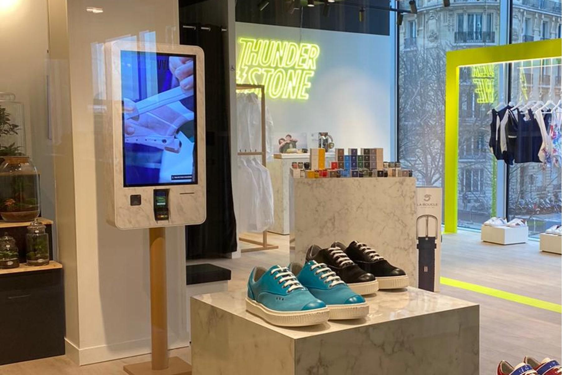 Intérieur de magasin de détail avec des chaussures en vitrine et un terminal de paiement Adyen.