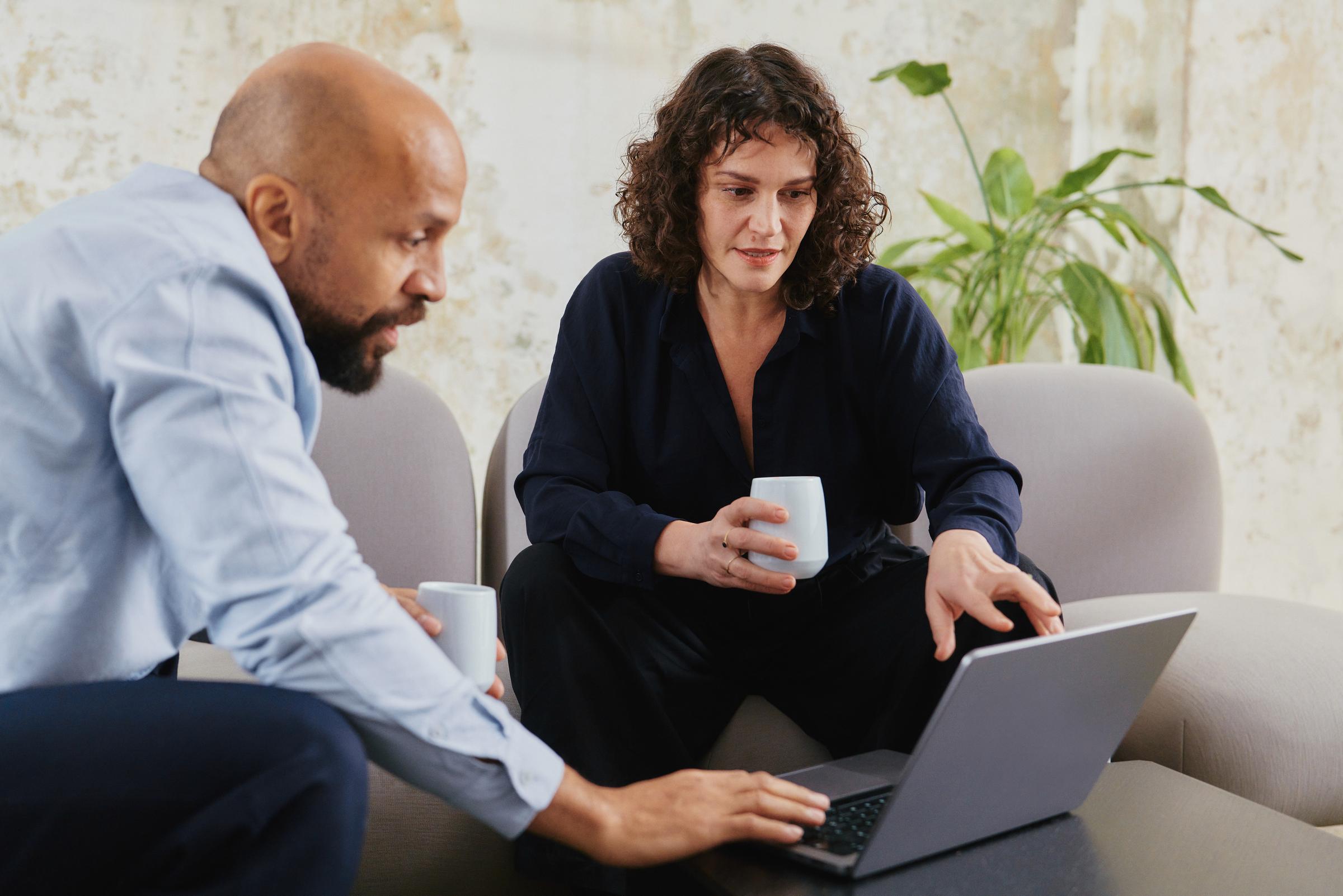 Collègues d'une entreprise de technologie Saas en réunion discutant sur un ordinateur portable
