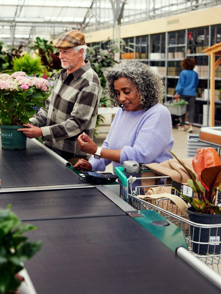 Woman making a payment at a garden center checkout with a man standing beside her.