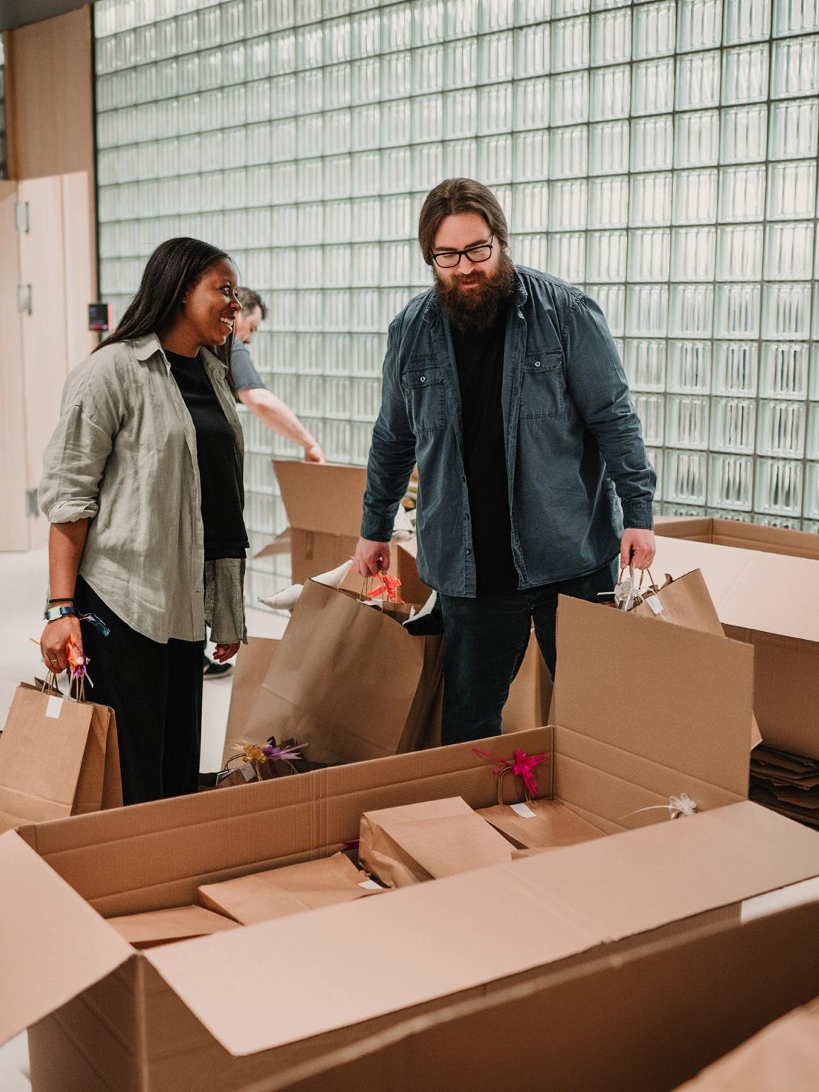 Dwie osoby stojące obok otwartych pudeł z przedmiotami w środku, wyglądające na to, że rozpakowują.