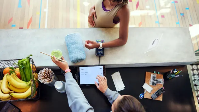 Person using a smartwatch to make a payment on an Adyen terminal at a gym.