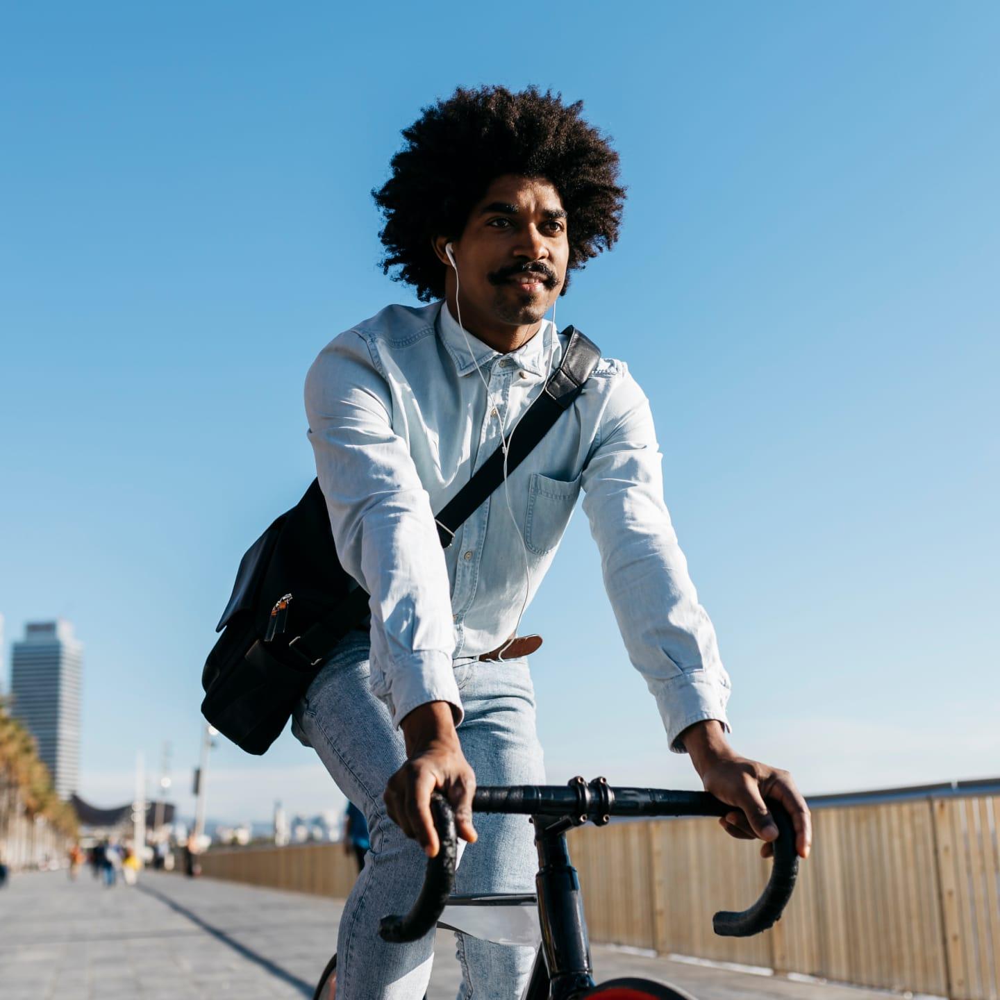 Hombre montando una bicicleta en un día soleado con cielos azules claros.